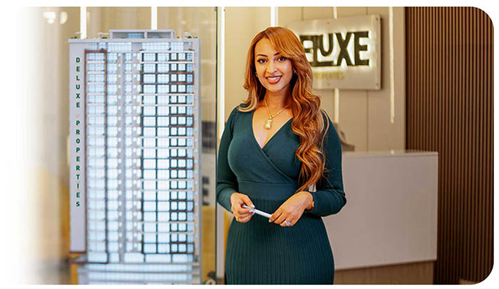 A Deluxe Properties advisor beside a scale model of a Deluxe tower